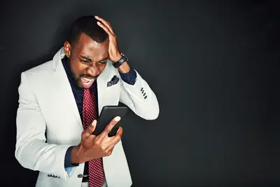 Frustrated man holding a phone that is not working as expected