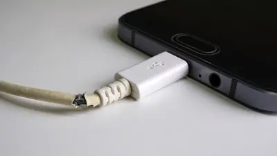 Smartphone plugged into a wall charger with its cable connected